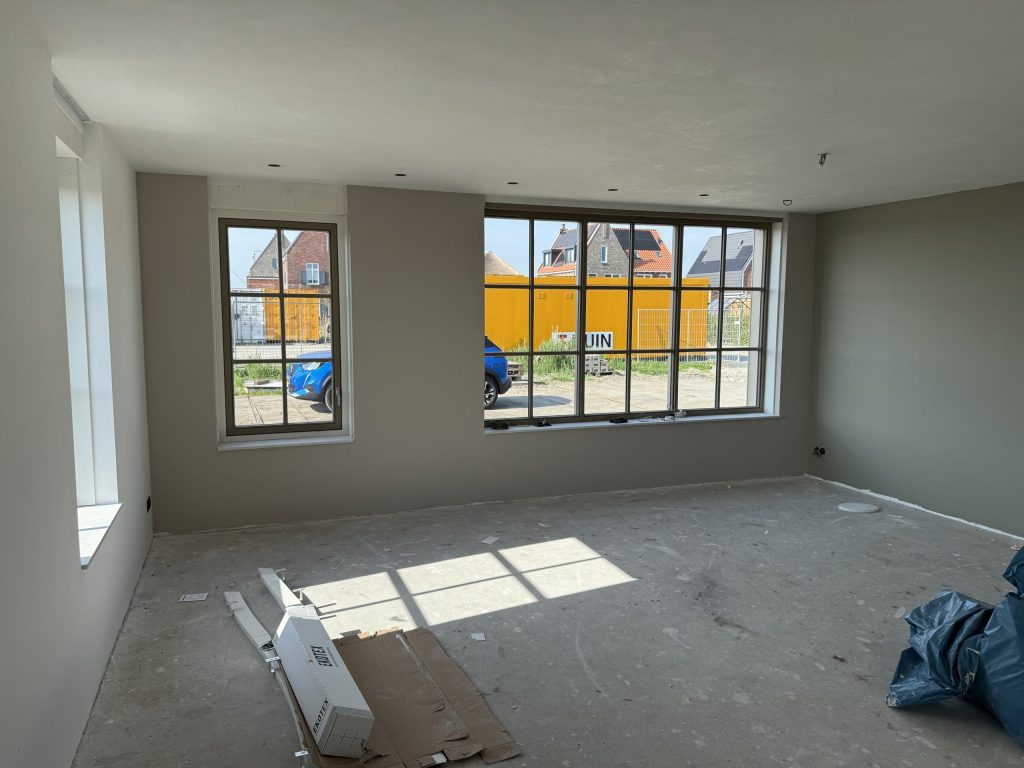 Nieuwe woonkamer met grote ramen en egaal gesausde wanden, nog zonder vloer