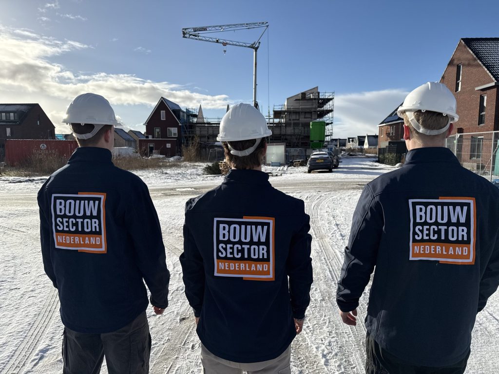 Drie medewerkers van Bouwsector Nederland met witte helm op een besneeuwde bouwplaats